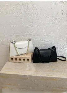 Detail of metal chain strap and silver buckle on chic matte leather crossbody bag
