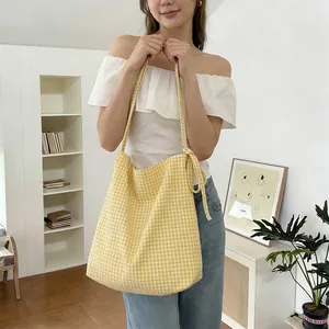 Detail of yellow gingham canvas tote bag featuring a decorative shoulder bow ribbon
