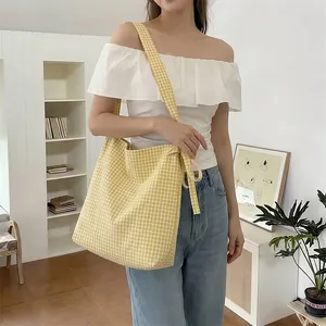Detail of yellow gingham canvas tote bag featuring decorative bow shoulder straps