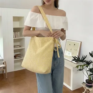 Detail of yellow gingham canvas tote bag featuring adjustable bow-knot shoulder straps