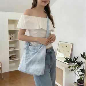 Detailed close-up of large light blue checkered canvas tote bag with wide strap