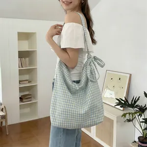 Detail of adjustable bow tie shoulder strap on light blue gingham canvas tote bag
