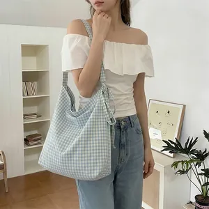 Detail of blue and white checkered canvas tote bag with a decorative bow knot strap