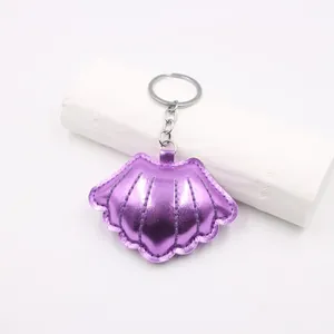Detailed view of sea shell leather keychain with purple metallic finish and silver ring