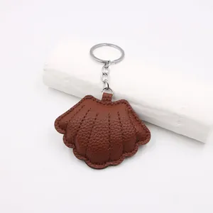 Detail of deep brown shell leather keychain with lychee texture and silver metal ring