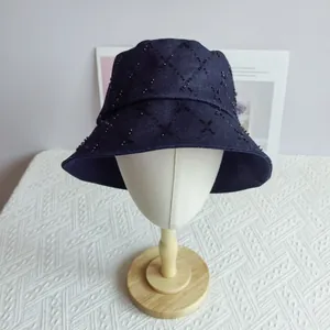 Detailed view of dark blue denim bucket hat with hand-sewn black beaded diamond patterns
