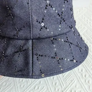 Detail view of denim bucket hat with black sequins and beads in a rhombic pattern
