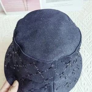 Close-up of blue denim bucket hat with silver sequin quilted patterns and embroidery