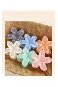 Close-up of six colorful flower hair claw clips in pastel macaron shades on jute