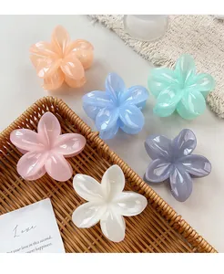 Detailed view of candy-colored floral hair claws in resin on a wicker tray