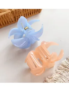 Macro detail of wave-shaped hair claws in light blue and orange with golden springs