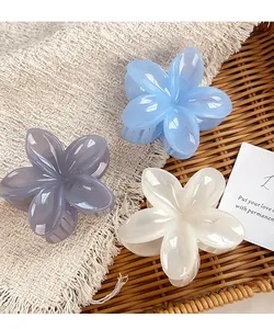 Detailed view of large flower-shaped hair claws in blue, grey, and cream acrylic