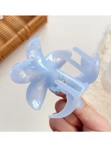 Detail of light blue floral hair claw clip in translucent material held by hand