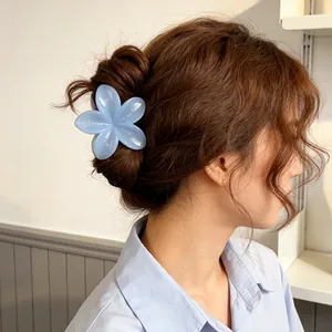 Light blue flower claw clip with glossy finish worn by a model in a casual hairstyle