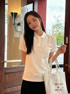 Detail of Korean style smile embroidered striped canvas tote bag with a white polo shirt