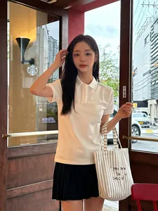 Close-up of a striped canvas tote bag with embroidery held by a model in a café