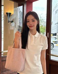 Detail of pink striped canvas tote bag with embroidery held by model in polo shirt