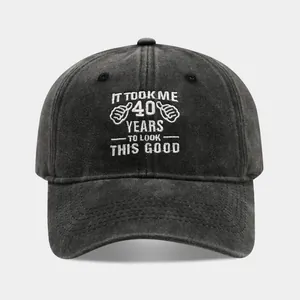 Detail of white embroidery text on washed black cotton fabric of a 40th birthday baseball cap