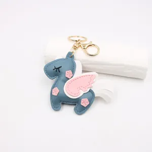 Detail of handmade blue leather unicorn bag charm with pink wings and gold keychain hardware