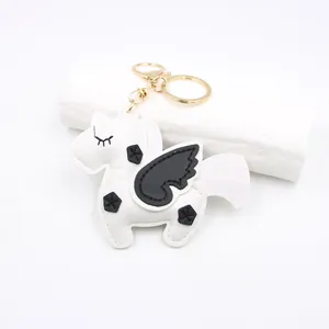 Detail shot of a handmade leather unicorn keychain with black wings and gold metal ring