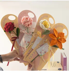 Close-up of handmade crochet carnations and roses in festive gift packaging