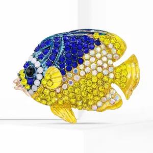 Dettaglio della spilla a pesce con strass gialli e blu su una base bianca elegante