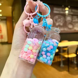 Close-up of pink and blue glowing drift bottle keychains with colorful sand and sequins