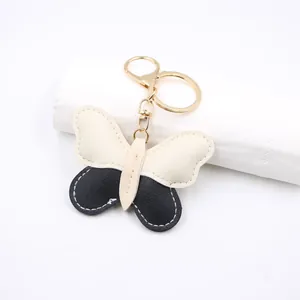 Close-up of butterfly leather keychain with black and cream contrast stitching