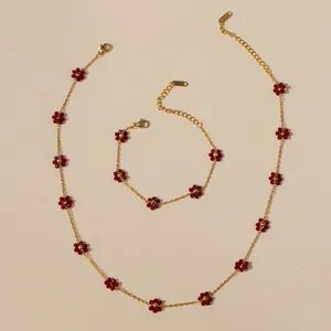 Detail of bohemian stainless steel jewelry set with red beaded flowers and metal tags
