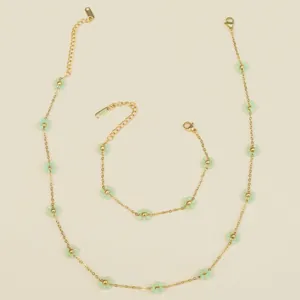 Detailed close-up of golden stainless steel chain with mint green beaded flower charm