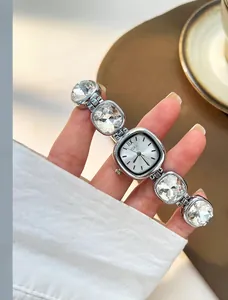Detail of luxury silver watch with crystal links and square dial on woman wrist