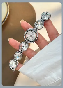 Close-up of luxury women's watch with crystal chain strap and rectangular silver dial