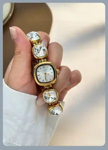 Macro detail of gold watch band featuring large cushion-cut crystals and metal chain