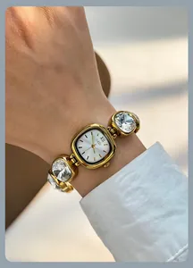 Close-up of gold tone watch with crystal chain strap and Roman numeral dial details