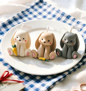 Three sitting 3D rabbit scented candles in beige, khaki and grey on a white plate