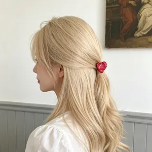 Pince à cheveux rouge en forme de cœur portée sur des cheveux blonds bouclés