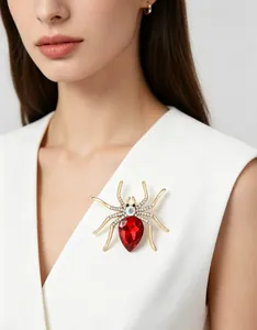 Detail view of gold spider brooch with large red teardrop gem and white rhinestones