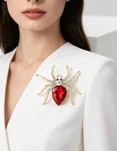 Detailed view of crystal spider brooch with red pear-cut gemstone on white blazer