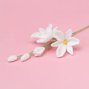 Handmade white crochet lily flowers with yellow accents on a soft pink background