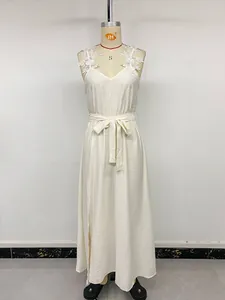 Detail of floral lace applique on shoulder and V-neckline of a cream maxi dress