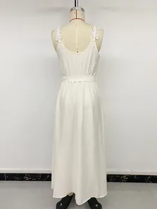 Detail of white maxi dress featuring delicate lace floral shoulder straps and a back tie belt