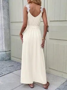 Close-up of elegant white floral lace appliqué on a cream backless summer maxi dress