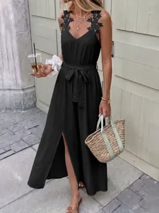 Detail of black V-neck maxi dress featuring lace floral appliques and waist tie ribbon