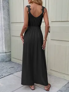 Detail of elegant black slit maxi dress showing delicate lace flower strap on open back