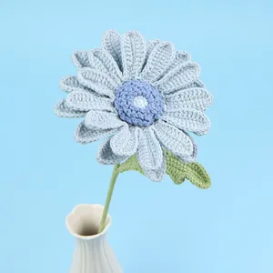 Handmade light blue crochet daisy flower with green stem and leaf in a white vase
