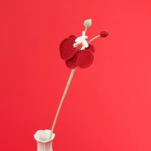 Handmade crochet orchid flower with deep red petals in a white ceramic vase