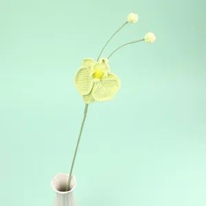 Handmade crochet orchid flower in light green with yellow center in white ceramic vase