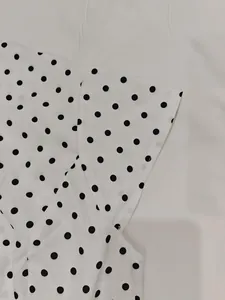 Dettaglio ravvicinato del tessuto bianco a pois neri che mostra cuciture e trama