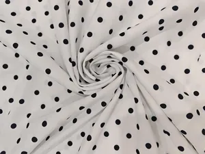 Macro di tessuto in chiffon bianco a pois neri che mostra una texture drappeggiata