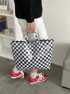 Detail of checkered tote bag showing waterproof fabric texture and Tote Bag lettering